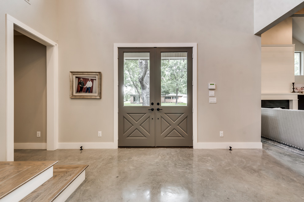 Imagen de puerta principal campestre con paredes beige, suelo de cemento, puerta doble, puerta gris y suelo beige