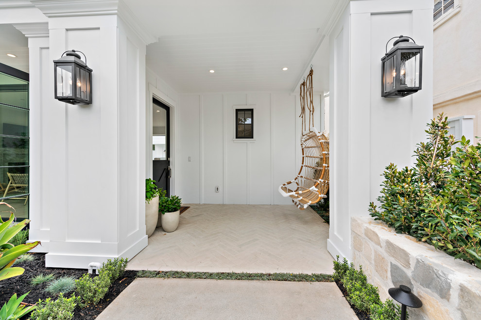 This is an example of a beach style foyer in Los Angeles with white walls, a single front door, a black front door and beige floors.