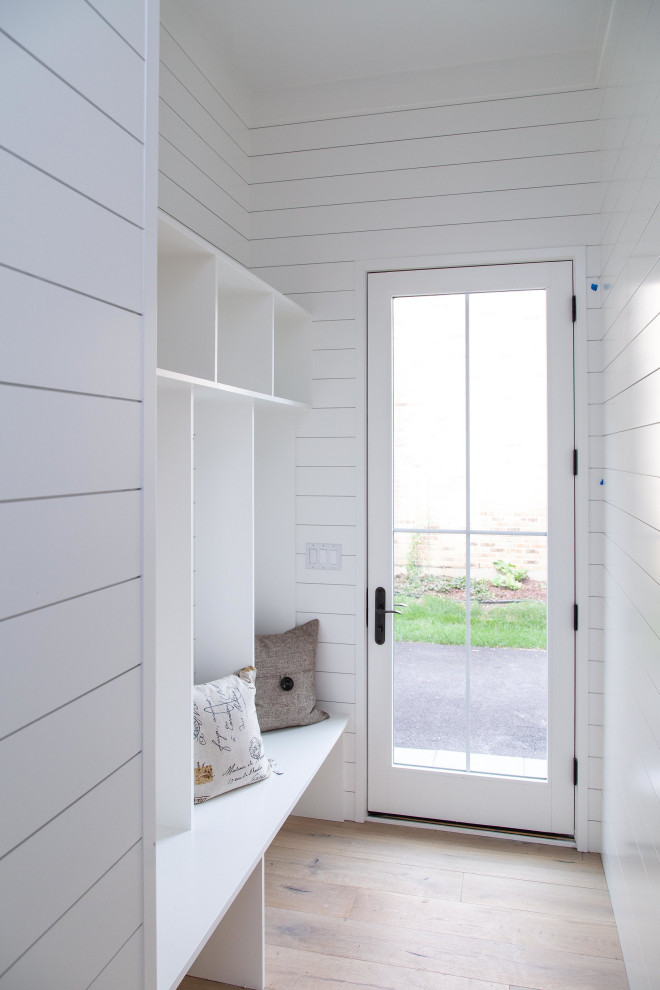 This is an example of a small farmhouse boot room in Chicago with white walls, light hardwood flooring, a single front door, a white front door and beige floors.