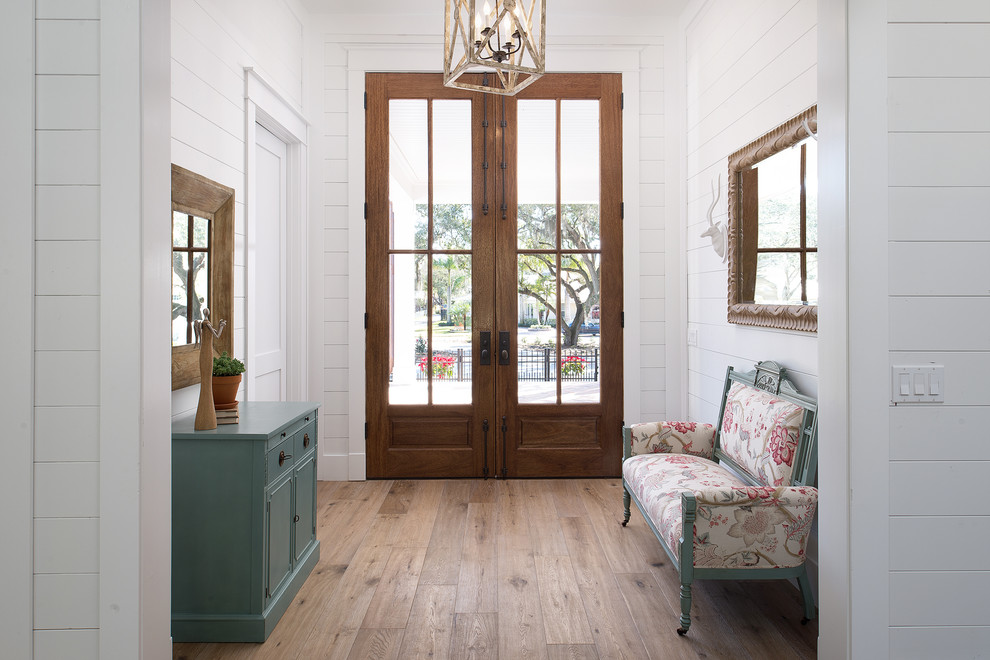 This is an example of a farmhouse hallway in Tampa with white walls, light hardwood flooring, a double front door, a dark wood front door and beige floors.