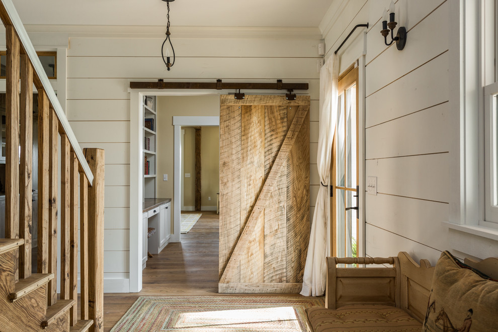 Ejemplo de entrada campestre grande con suelo de madera en tonos medios y paredes beige