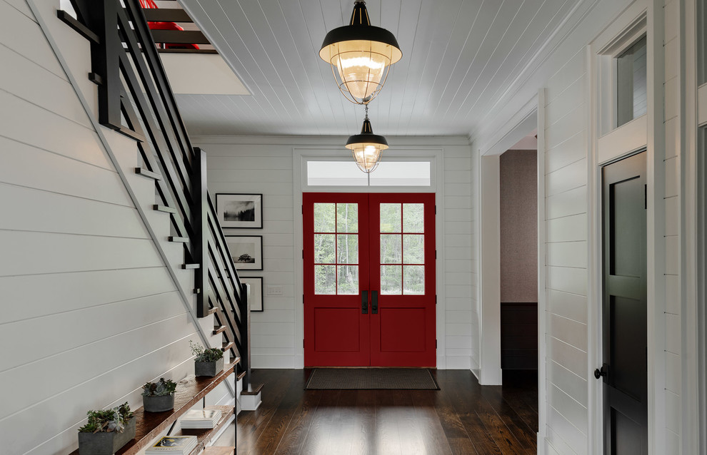 Exempel på en stor lantlig foajé, med vita väggar, mörkt trägolv, en dubbeldörr, en röd dörr och brunt golv