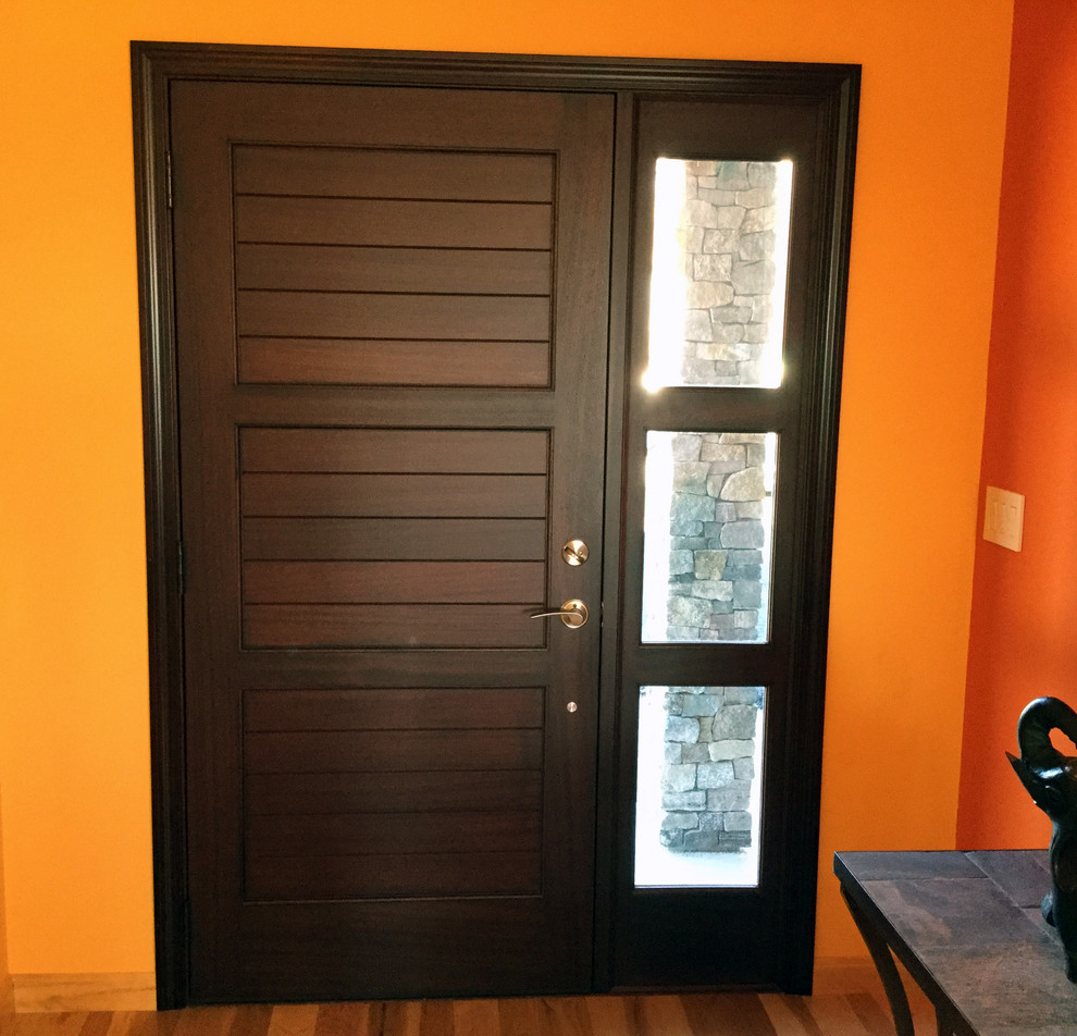 Example of a trendy medium tone wood floor entryway design in Other with orange walls and a dark wood front door