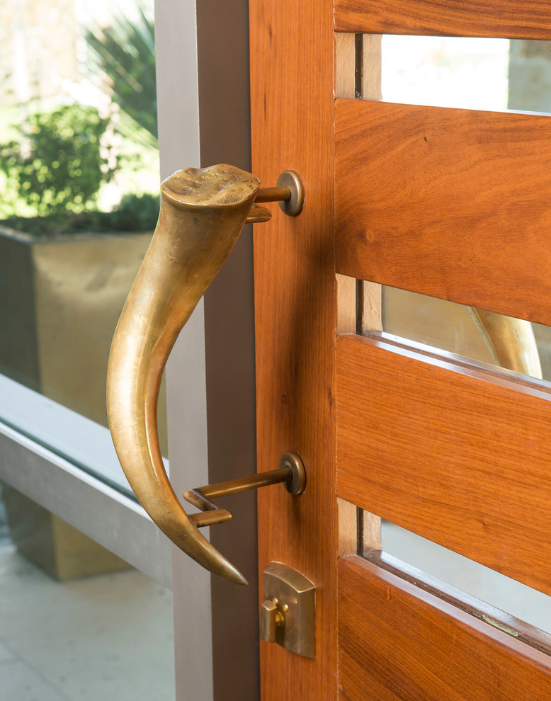 Réalisation d'une très grande porte d'entrée vintage avec un mur beige, un sol en carrelage de porcelaine, une porte pivot et une porte en bois brun.