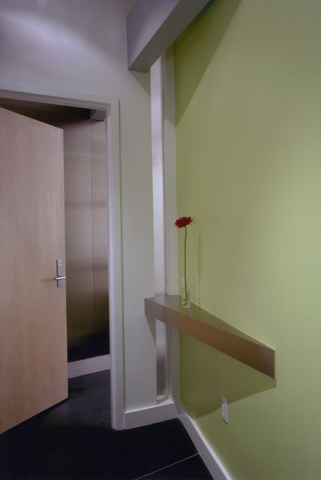 Idée de décoration pour un vestibule minimaliste avec un mur vert, une porte simple et une porte en bois clair.