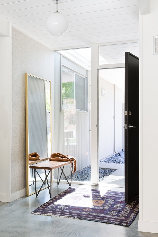 Идея дизайна: фойе в стиле ретро с серыми стенами, бетонным полом, одностворчатой входной дверью и черной входной дверью