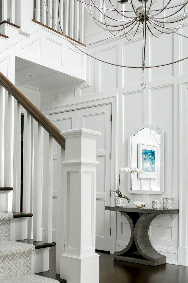 Réalisation d'un grand hall d'entrée tradition avec un mur blanc, parquet foncé, une porte simple et une porte en bois foncé.