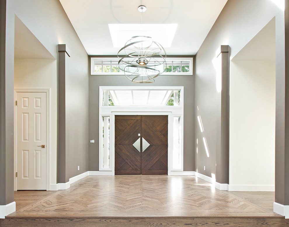 Aménagement d'une grande entrée contemporaine avec un couloir, un mur marron, un sol en bois brun, une porte double, une porte marron et un sol marron.