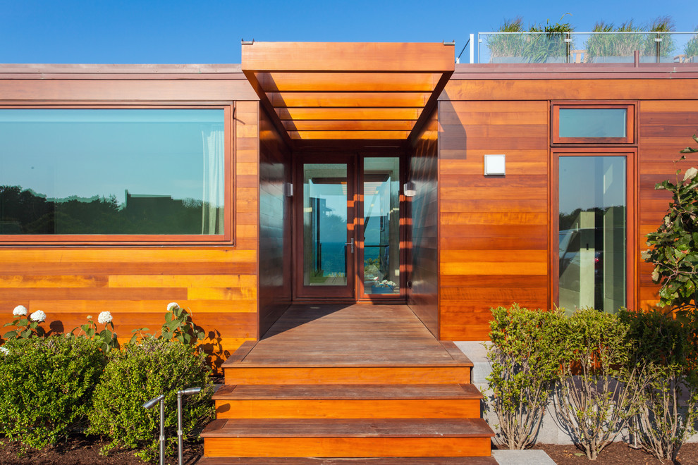 Cette image montre une grande porte d'entrée minimaliste avec un sol en bois brun, une porte simple et une porte en bois brun.