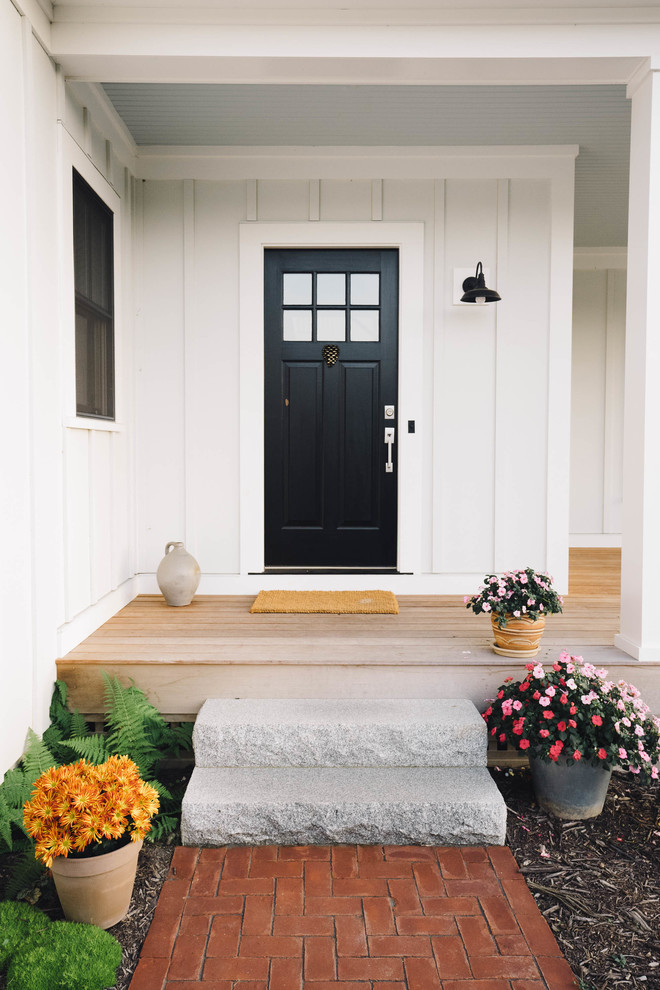 Cette image montre une porte d'entrée rustique de taille moyenne avec un mur blanc, parquet clair, une porte simple, une porte noire et un sol marron.
