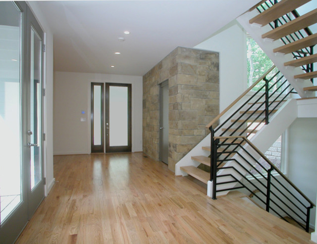 Huge minimalist light wood floor entryway photo in Atlanta with white walls and a dark wood front door