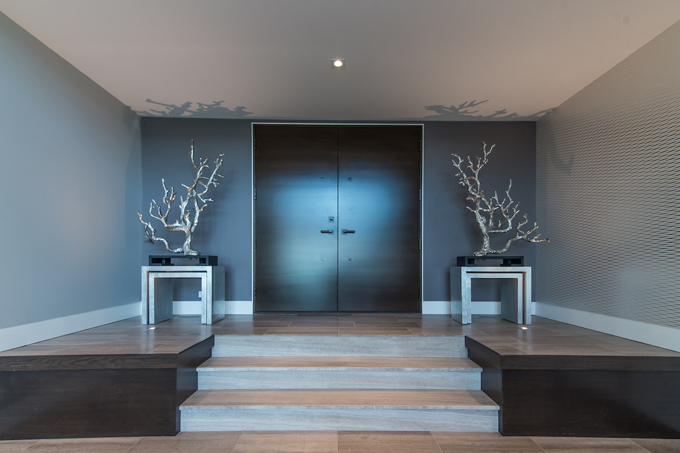 Diseño de puerta principal moderna grande con paredes grises, suelo de madera clara, puerta doble, puerta de madera oscura y suelo marrón
