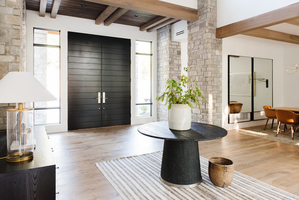 Imagen de distribuidor de estilo de casa de campo grande con paredes blancas, suelo de madera clara, puerta doble, puerta negra y suelo beige