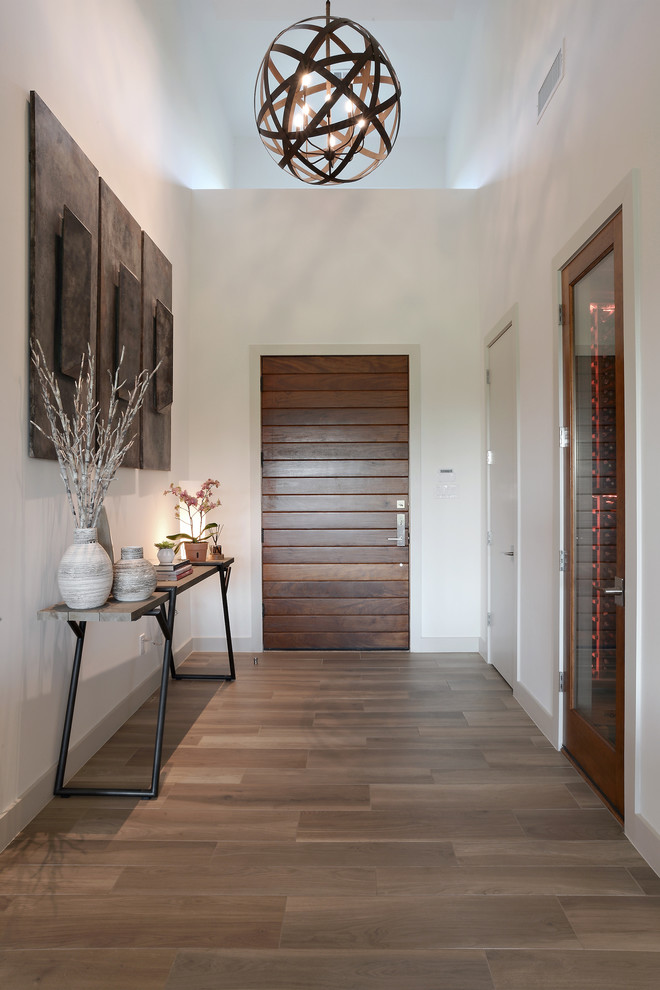 Пример оригинального дизайна: фойе среднего размера в стиле модернизм с белыми стенами, паркетным полом среднего тона, одностворчатой входной дверью, входной дверью из дерева среднего тона и коричневым полом