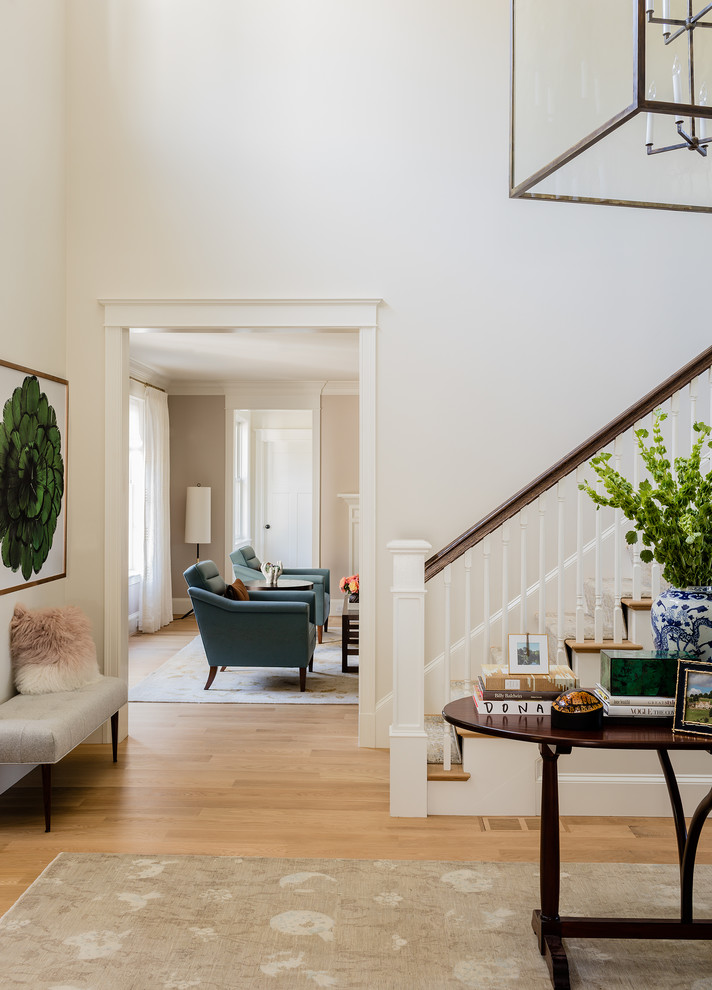 This is an example of a large classic foyer in Boston with white walls, light hardwood flooring and brown floors.