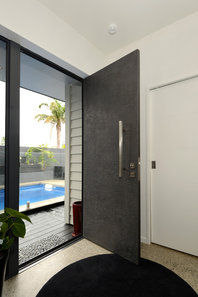 Modern inredning av en mellanstor ingång och ytterdörr, med vita väggar, betonggolv, en enkeldörr och en grå dörr