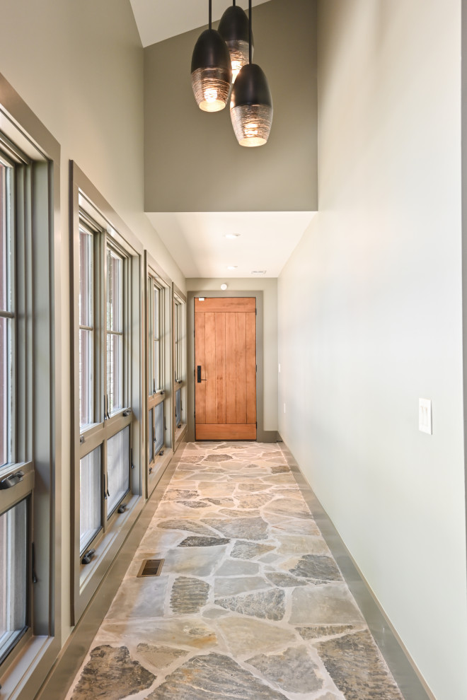 Cette photo montre une porte d'entrée montagne de taille moyenne avec un mur gris, une porte simple, une porte en bois brun et un sol gris.