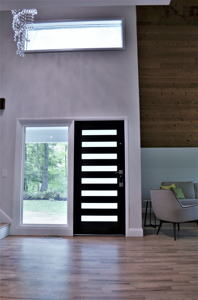 Пример оригинального дизайна: большое фойе в стиле ретро с серыми стенами, светлым паркетным полом, одностворчатой входной дверью, входной дверью из темного дерева и деревянным потолком