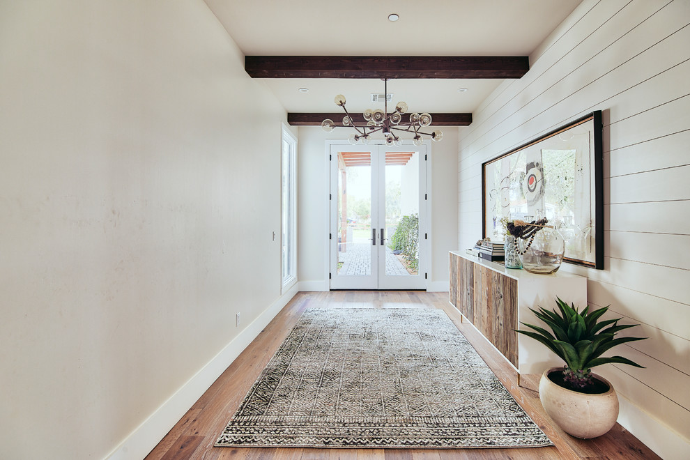 Example of a huge minimalist medium tone wood floor entryway design in Phoenix with a white front door and white walls
