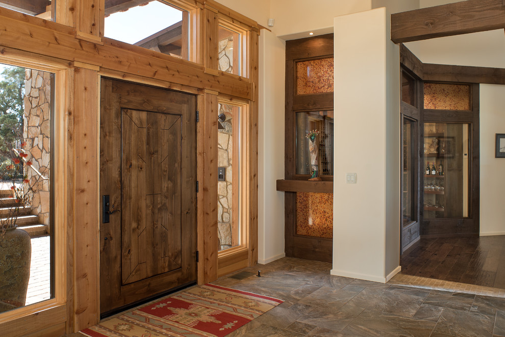フェニックスにある高級な巨大なサンタフェスタイルのおしゃれな玄関ロビー (ベージュの壁、セラミックタイルの床、木目調のドア) の写真