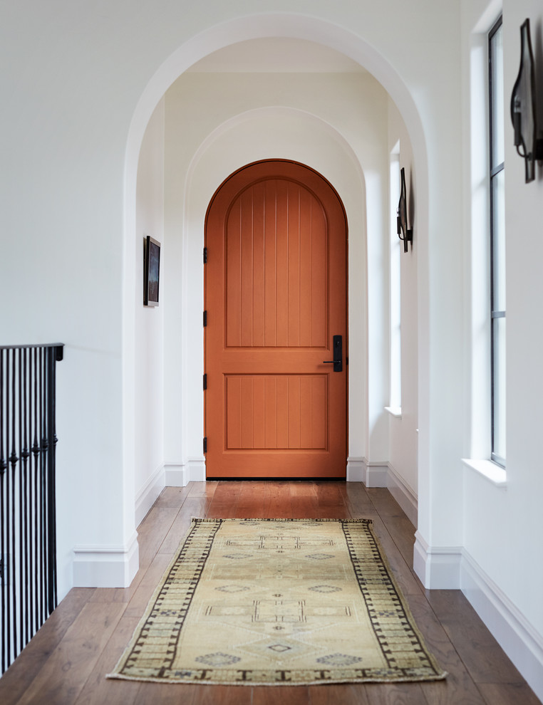 Medelhavsstil inredning av en mellanstor ingång och ytterdörr, med vita väggar, mellanmörkt trägolv, en enkeldörr, en orange dörr och brunt golv