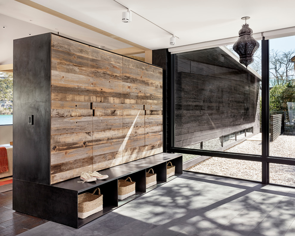 Idée de décoration pour une grande entrée minimaliste avec un vestiaire, une porte simple, une porte en bois foncé et un mur noir.
