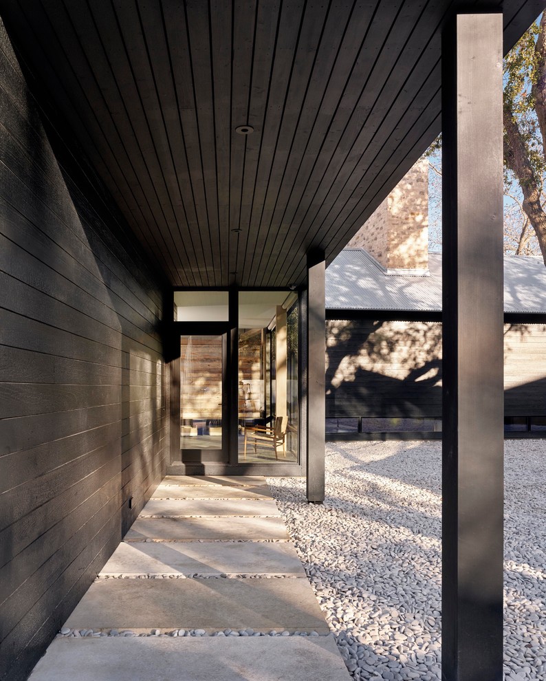 Réalisation d'une entrée minimaliste avec un vestiaire, un mur noir, une porte simple et une porte noire.