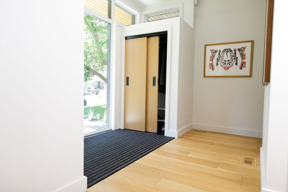 Idéer för en modern entré, med vita väggar, mellanmörkt trägolv och en enkeldörr