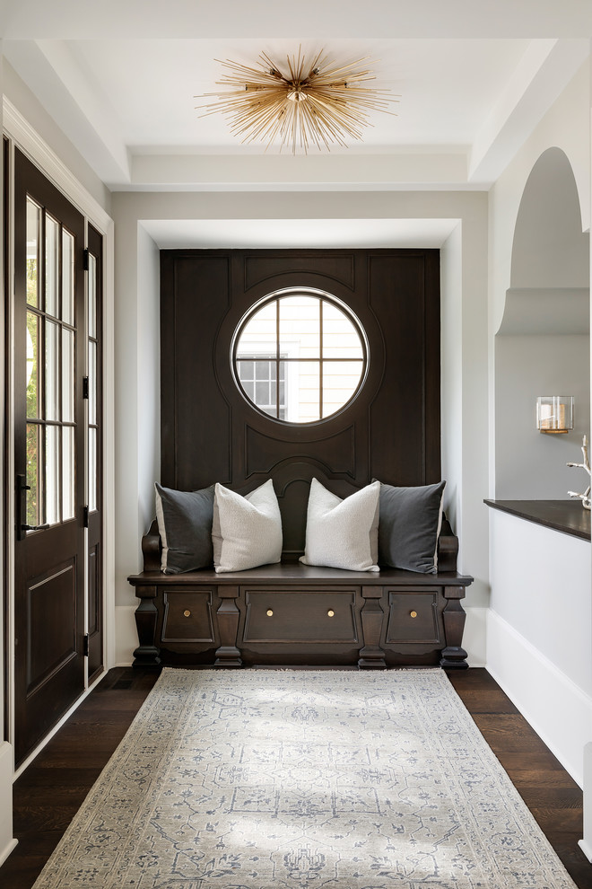 Стильный дизайн: узкая прихожая среднего размера в стиле неоклассика (современная классика) с серыми стенами, темным паркетным полом, одностворчатой входной дверью и входной дверью из темного дерева - последний тренд