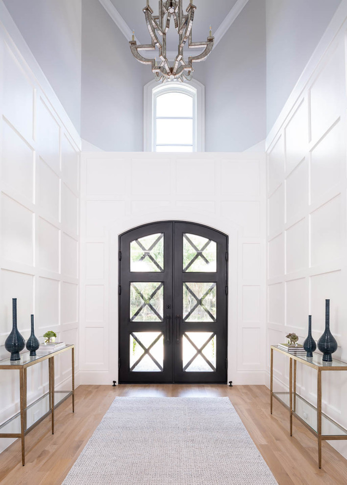 Пример оригинального дизайна: прихожая в стиле неоклассика (современная классика) с белыми стенами, паркетным полом среднего тона, поворотной входной дверью, черной входной дверью, коричневым полом, сводчатым потолком и панелями на части стены