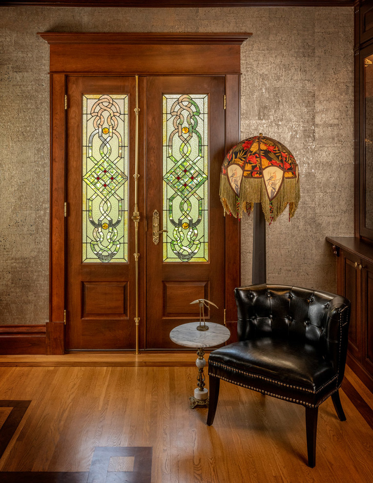 Imagen de entrada clásica de tamaño medio con suelo de madera en tonos medios, suelo marrón, paredes grises, puerta doble y puerta de madera en tonos medios