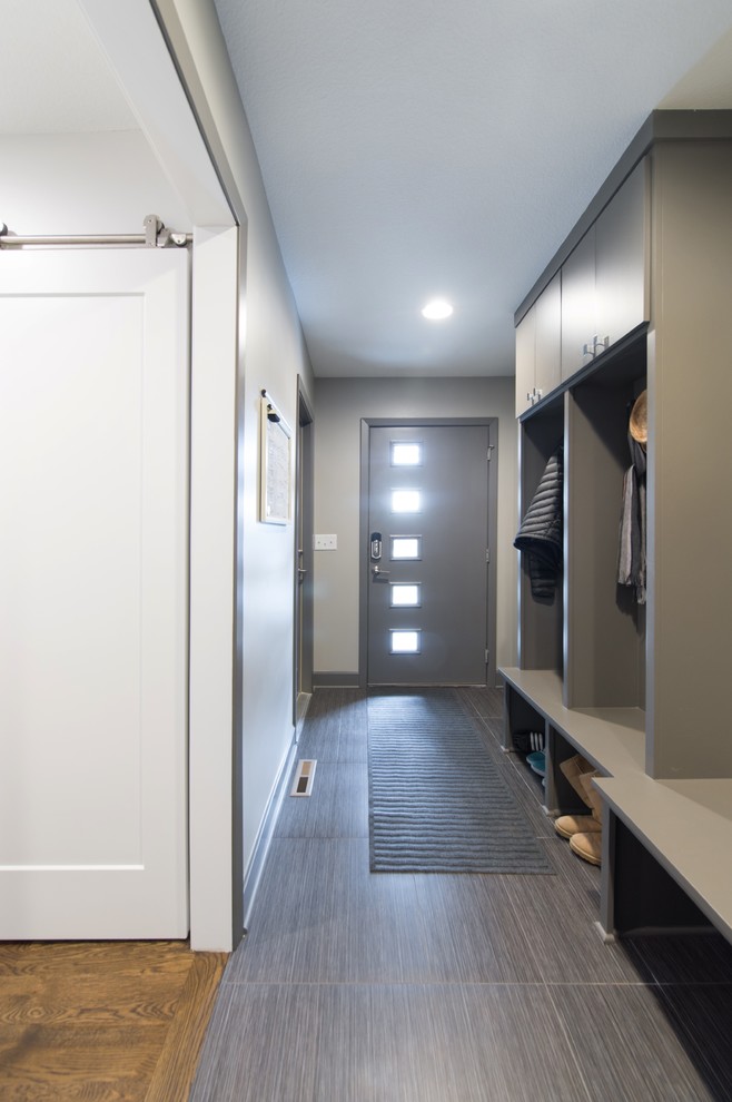 Cette image montre une entrée design de taille moyenne avec un vestiaire, un mur gris, un sol en vinyl, une porte simple et une porte grise.