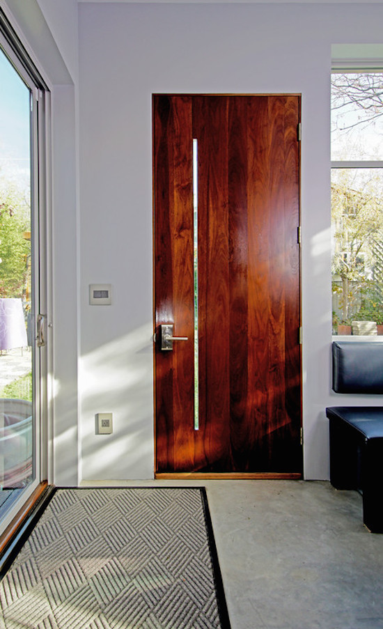 Ispirazione per una porta d'ingresso contemporanea di medie dimensioni con pareti bianche, pavimento in cemento, una porta singola e una porta in legno bruno