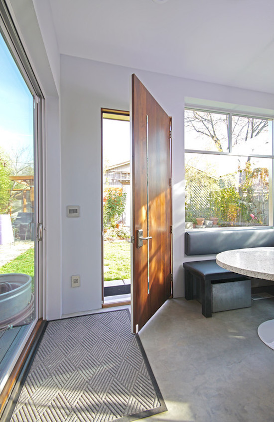 Cette image montre une porte d'entrée design de taille moyenne avec un mur blanc, sol en béton ciré, une porte simple et une porte en bois brun.