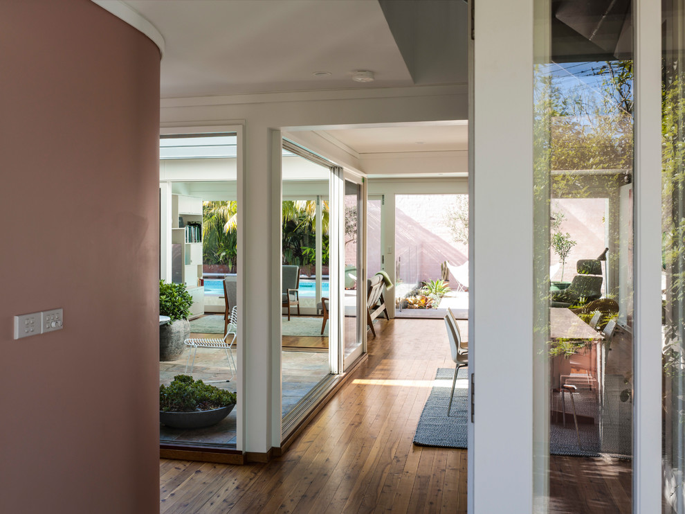 Ispirazione per una porta d'ingresso moderna di medie dimensioni con pareti rosa, parquet chiaro, una porta a due ante, una porta bianca e pavimento marrone