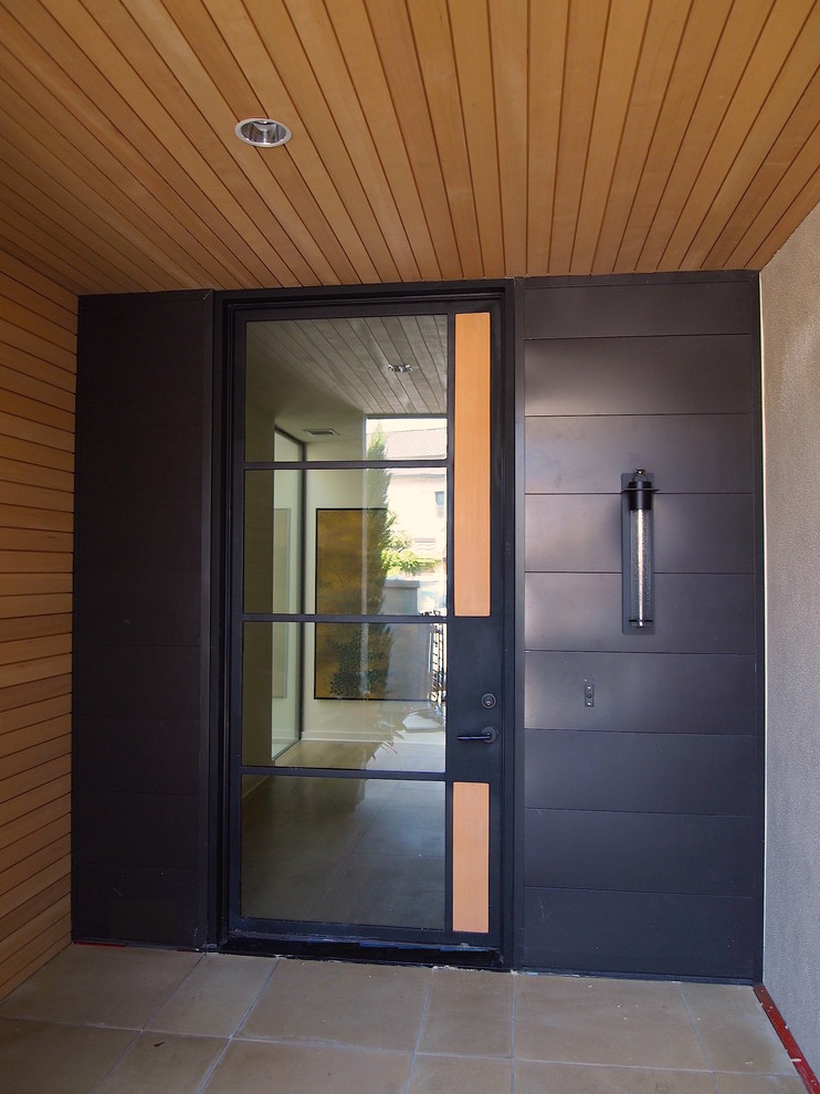Bild på en mellanstor funkis entré, med grå väggar, betonggolv, en dubbeldörr och en svart dörr
