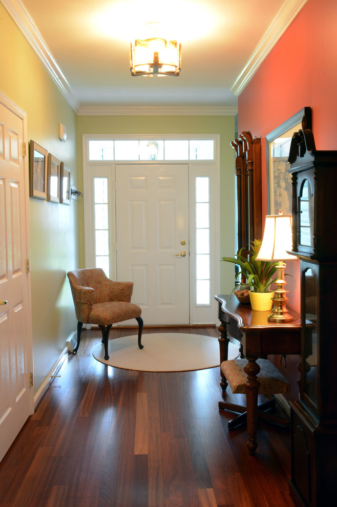 Immagine di un ingresso classico di medie dimensioni con pareti multicolore, pavimento in legno massello medio, una porta singola, una porta bianca e pavimento marrone