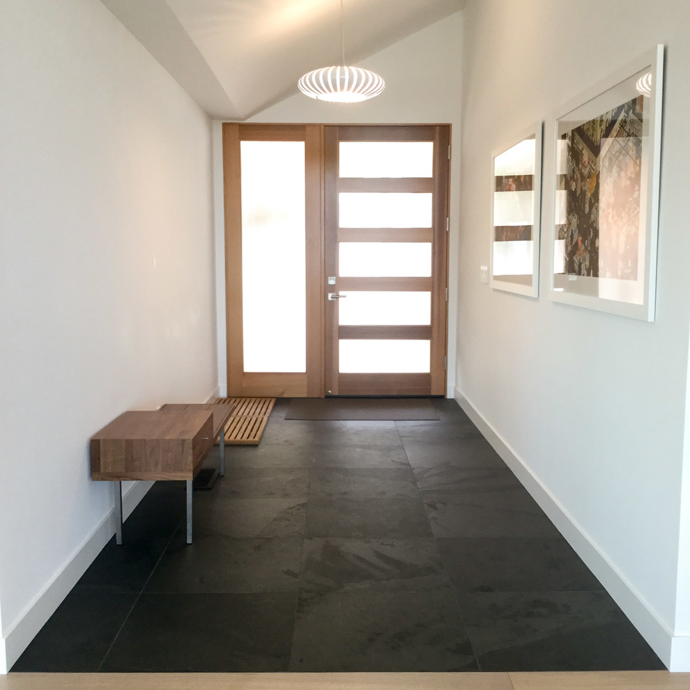Esempio di un corridoio design di medie dimensioni con pareti bianche, pavimento in ardesia e una porta in legno bruno