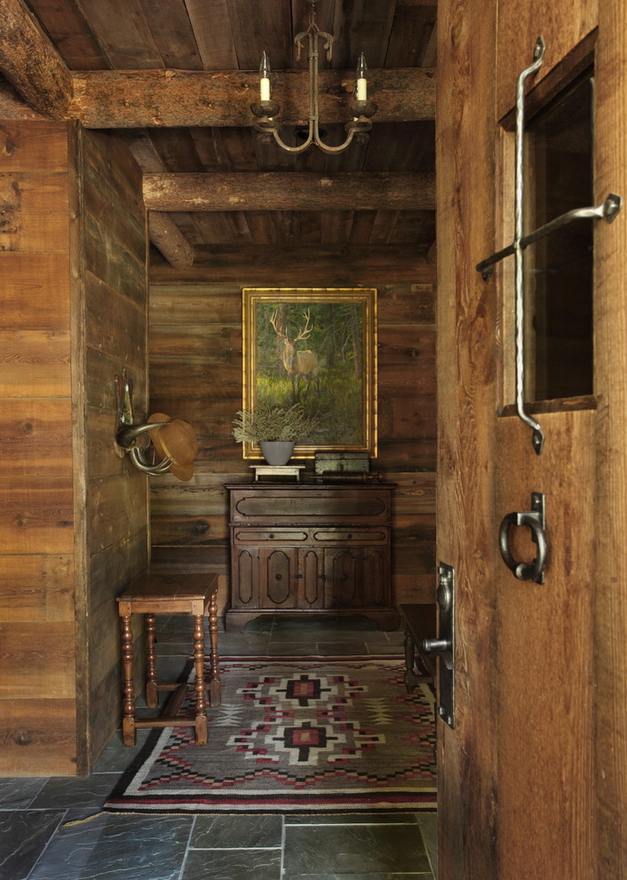 他の地域にある高級な広いラスティックスタイルのおしゃれな玄関ドア (スレートの床、茶色い壁、木目調のドア) の写真