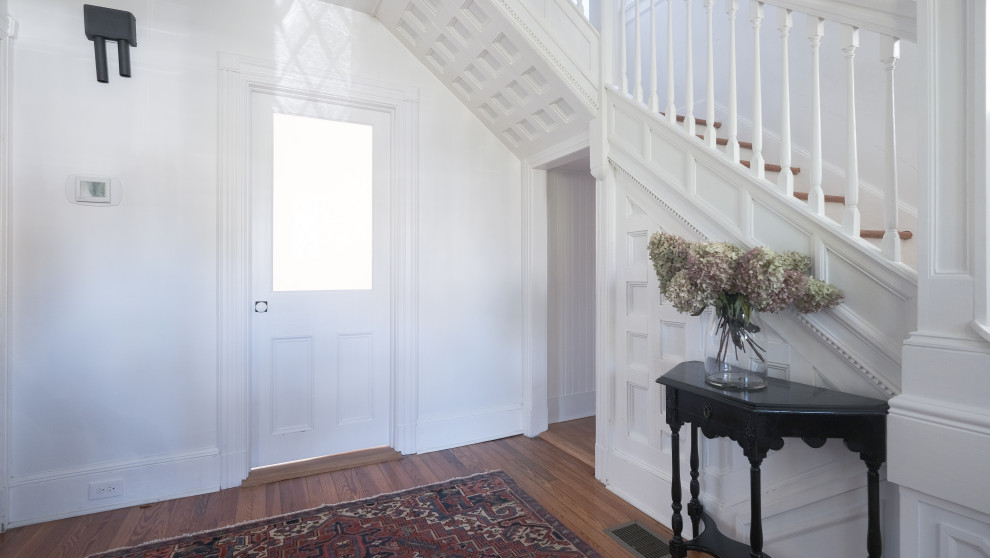 Ispirazione per una porta d'ingresso country di medie dimensioni con pareti bianche, pavimento in legno massello medio, una porta singola, una porta bianca e pavimento marrone