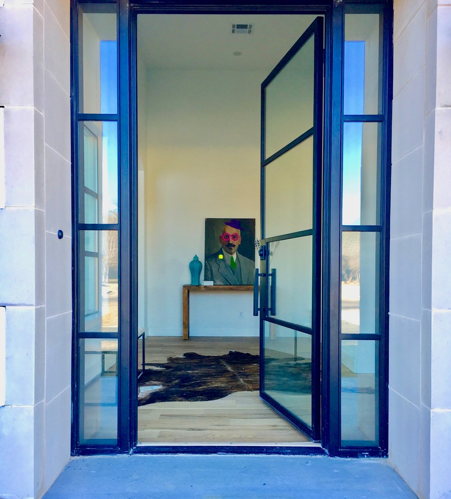 На фото: входная дверь среднего размера в современном стиле с белыми стенами, светлым паркетным полом, одностворчатой входной дверью, стеклянной входной дверью и коричневым полом