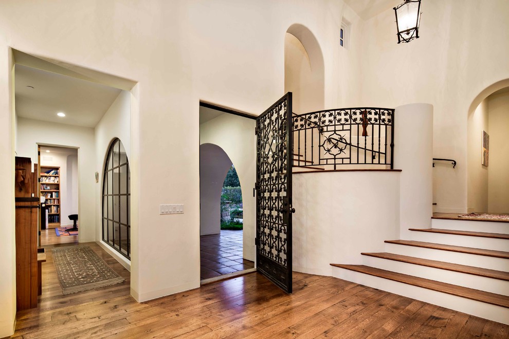 Mid-sized tuscan medium tone wood floor entryway photo in Santa Barbara with white walls and a metal front door