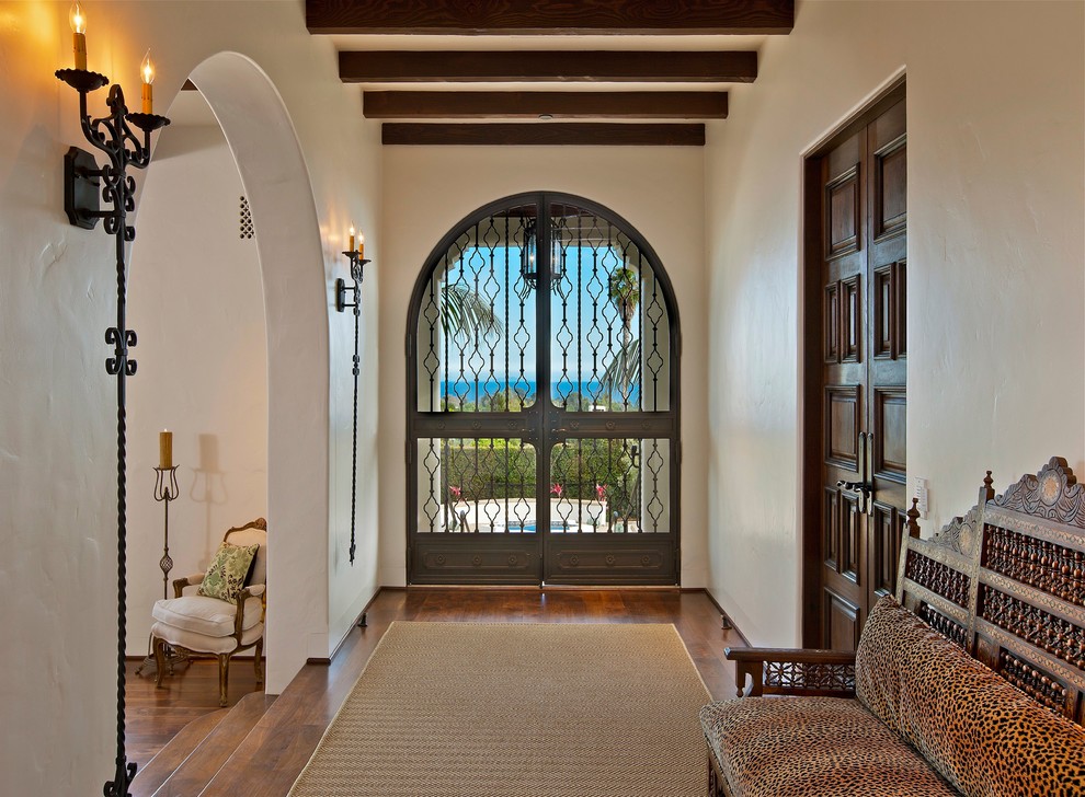 На фото: узкая прихожая в средиземноморском стиле с белыми стенами и двустворчатой входной дверью