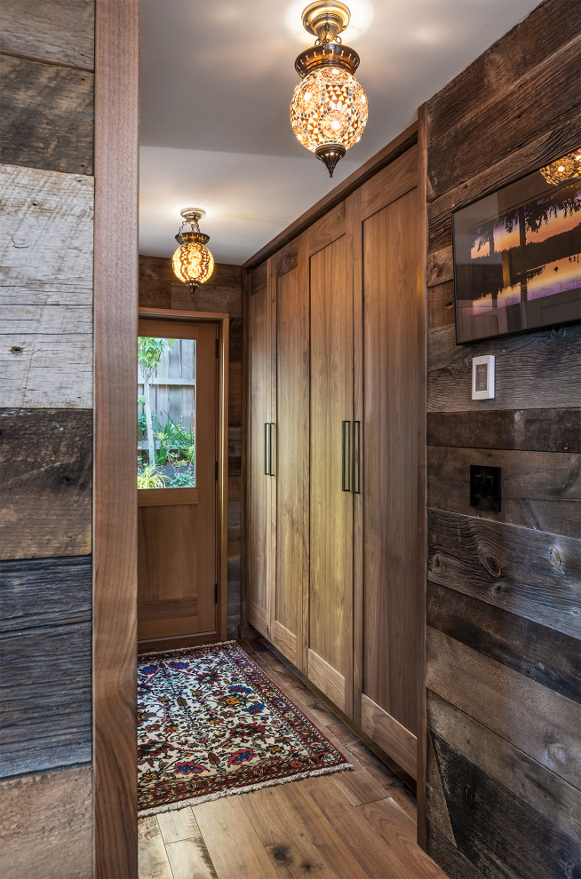 Ejemplo de distribuidor rústico de tamaño medio con paredes marrones, suelo de madera en tonos medios, puerta simple, puerta de madera en tonos medios y suelo marrón