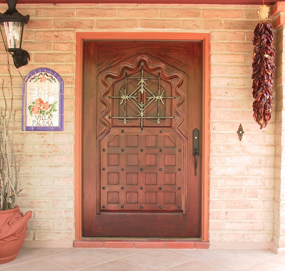 Cette photo montre une porte d'entrée chic de taille moyenne avec un mur orange, tomettes au sol, une porte simple et une porte en bois foncé.