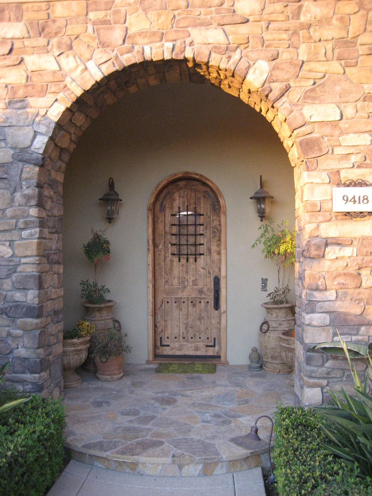 Imagen de puerta principal rústica de tamaño medio con paredes blancas, puerta simple y puerta de madera en tonos medios