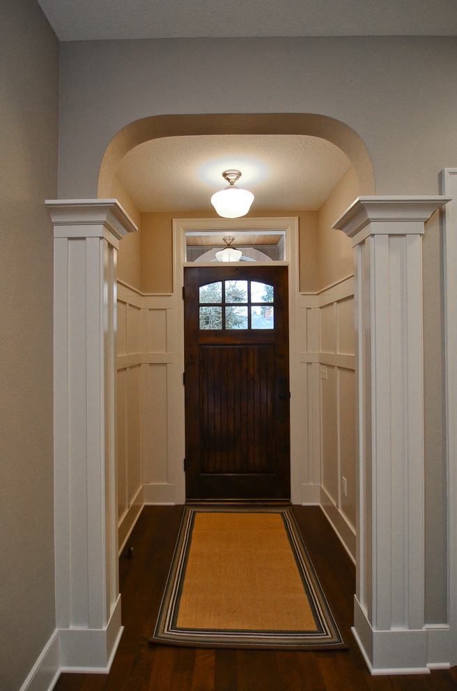 Diseño de entrada clásica de tamaño medio con paredes beige, suelo de madera en tonos medios y puerta de madera en tonos medios