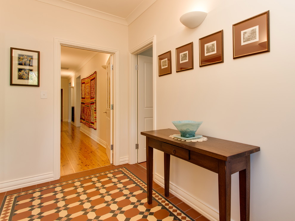 Diseño de vestíbulo clásico de tamaño medio con paredes blancas, suelo de baldosas de terracota y puerta simple