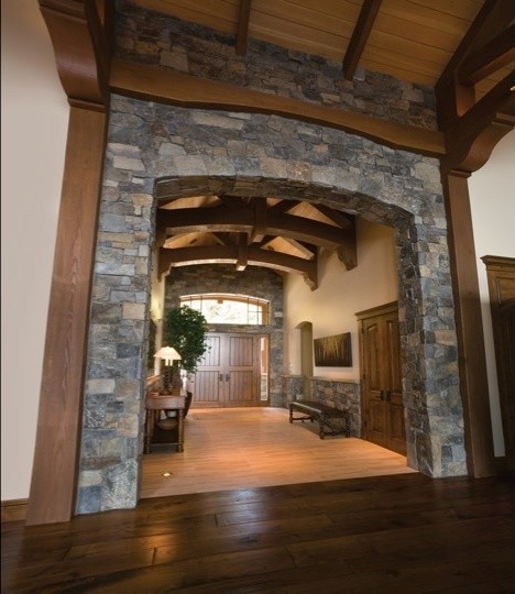 На фото: огромная входная дверь в классическом стиле с коричневыми стенами, темным паркетным полом, двустворчатой входной дверью, входной дверью из дерева среднего тона и коричневым полом