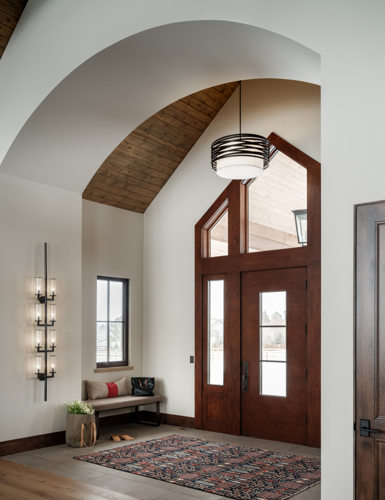 デンバーにあるラグジュアリーな広いラスティックスタイルのおしゃれな玄関 (ライムストーンの床、濃色木目調のドア、三角天井) の写真